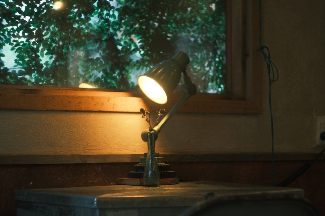 Vintage typewriter on a wooden desk lit by a lamp in a dim study